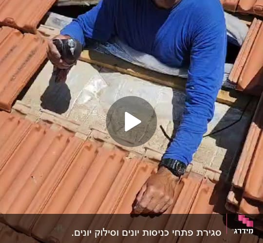אדם עובד על גג רעפים עם כלי עבודה ביד
